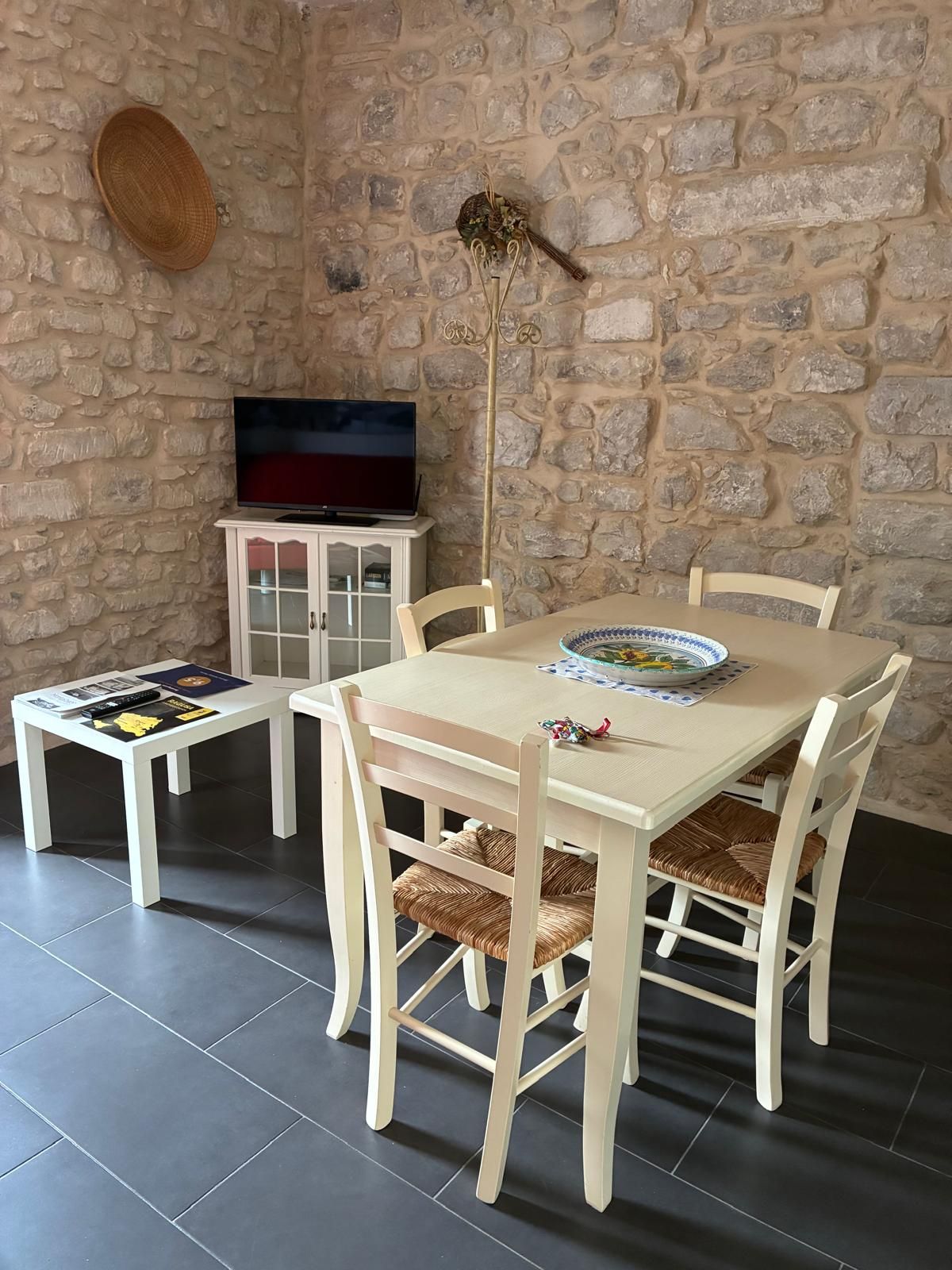 A dining area with a stone wall, a television on a cabinet, and a table set with plates and a placemat.
