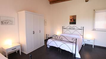 A bedroom with a bed, a wardrobe, a bedside table, and a window.
