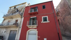 A red building with balconies, a garage door, and a small sign. - Reusia Holiday Home (Ragusa)