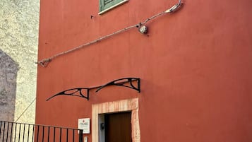 Un edificio rojo con una puerta marrón, una ventana verde y una valla de metal.