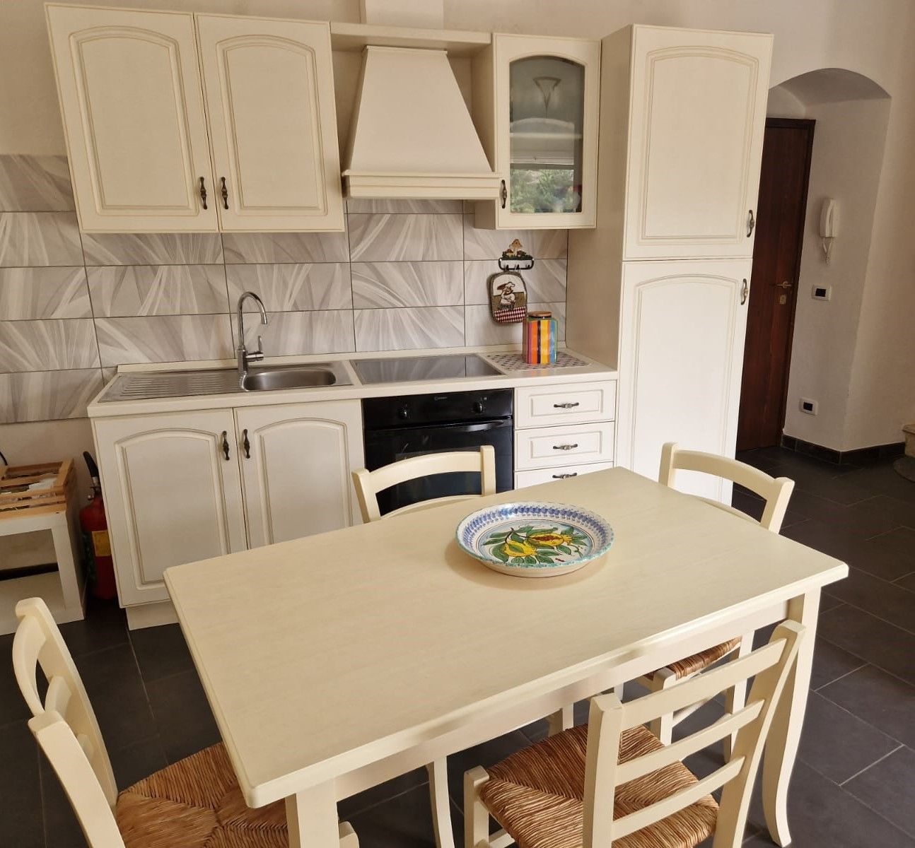 A kitchen with white cabinets, a sink, and a dining table with chairs.