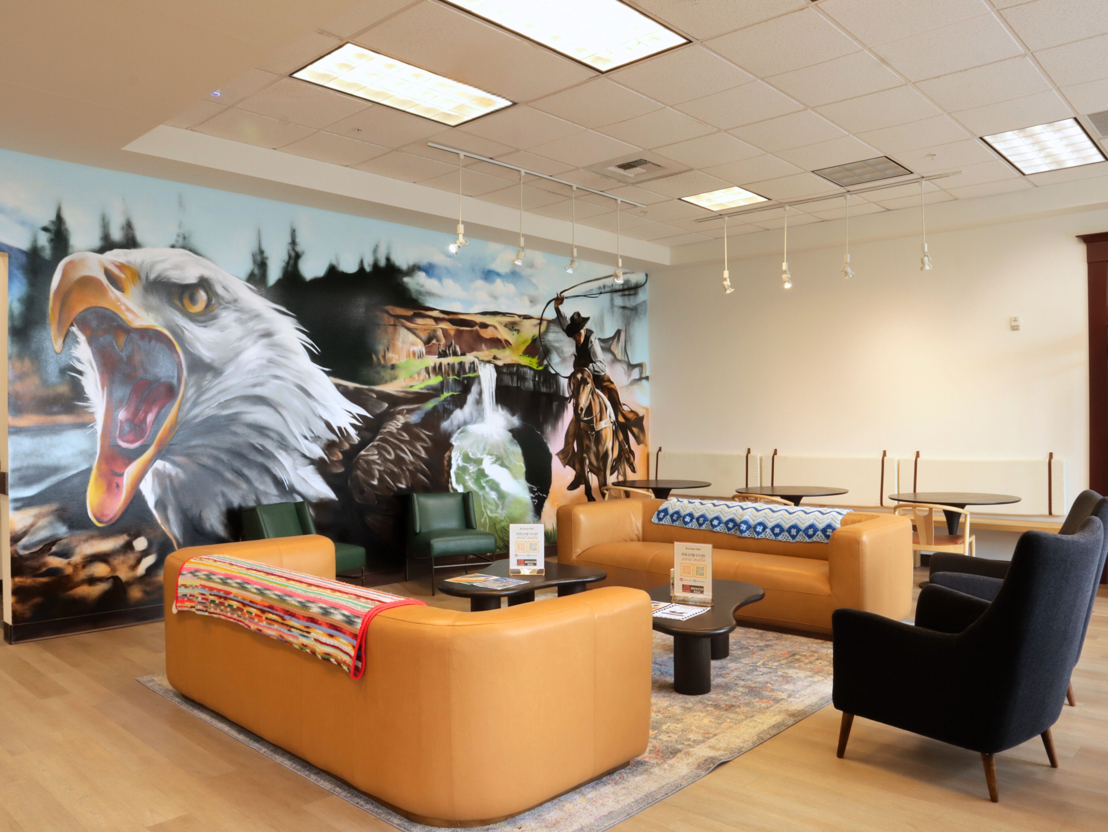 A hotel lobby with a large mural, leather seating, and a reception desk.