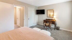 Ein Hotelzimmer mit einem Bett, einem Schreibtisch mit Stuhl, einem Fernseher und einem Spiegel.
