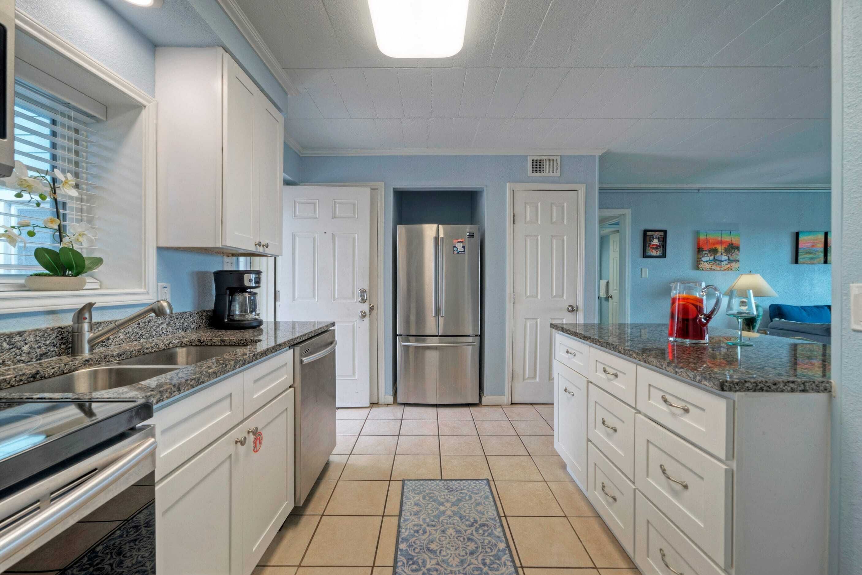 A kitchen with white cabinets, a stainless steel refrigerator, and a granite countertop.