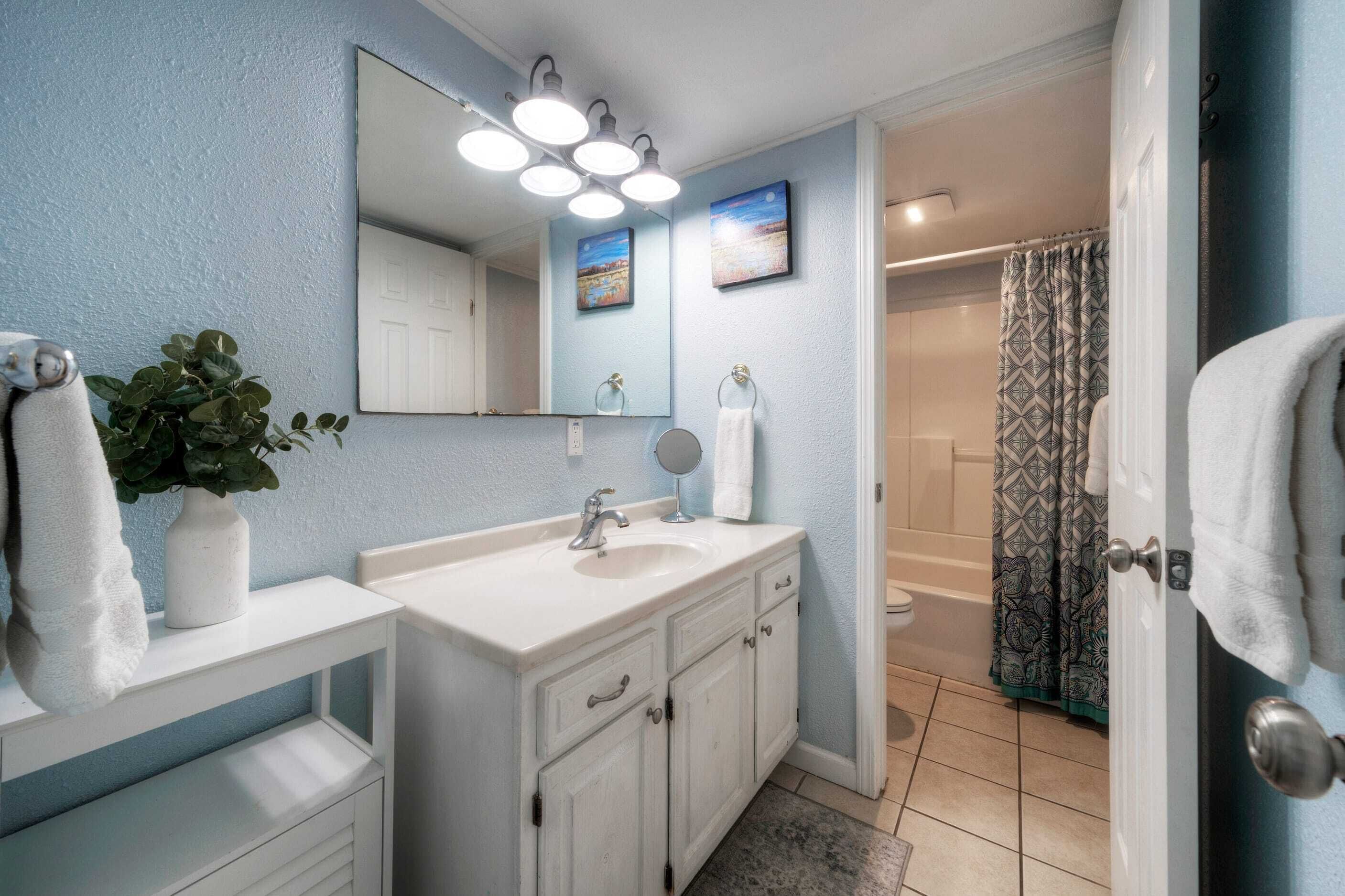 A bathroom with a white vanity, a large mirror, and a shower curtain.