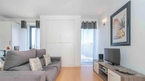 Un salon moderne avec un canapé gris, un téléviseur à écran plat et un meuble en bois.
