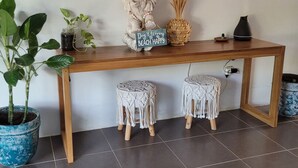 Une table en bois, des tabourets en macramé, un ananas décoratif, une pancarte sur laquelle on peut lire « Ne vous inquiétez pas, profitez de la plage », et une petite statue.