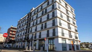 Un immeuble à plusieurs étages doté d’une architecture moderne, caractérisé par une série de balcons et de grandes fenêtres.