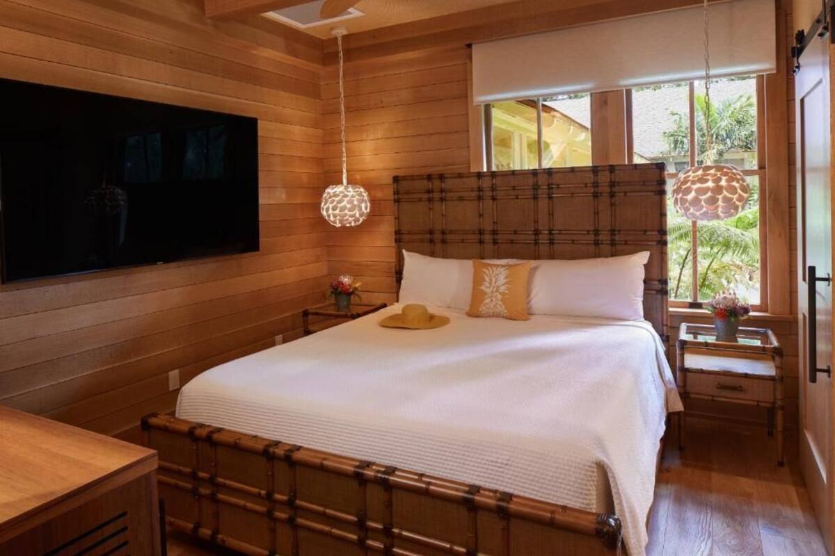 Una camera da letto con un letto grande, pareti in legno, una televisione e una finestra vista verde.