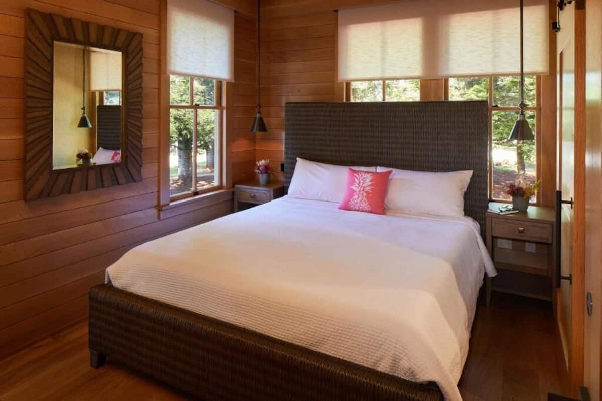 Una camera da letto con un letto grande, pareti in legno, uno specchio e una finestra con persiane.