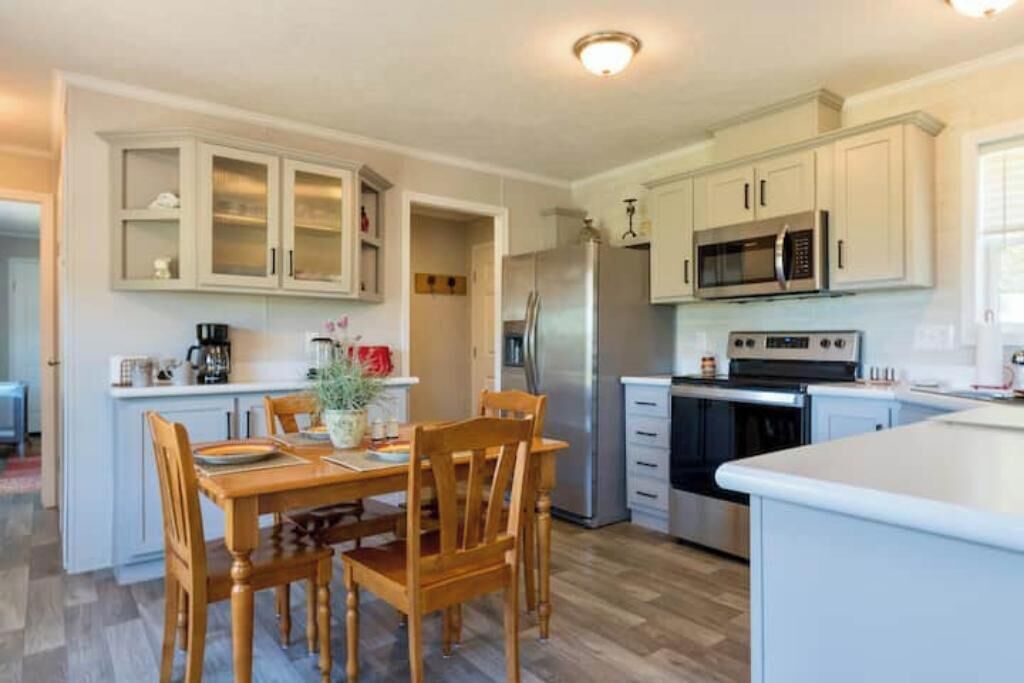 Una cocina moderna con armarios blancos, electrodomésticos de acero inoxidable y una mesa de comedor de madera.