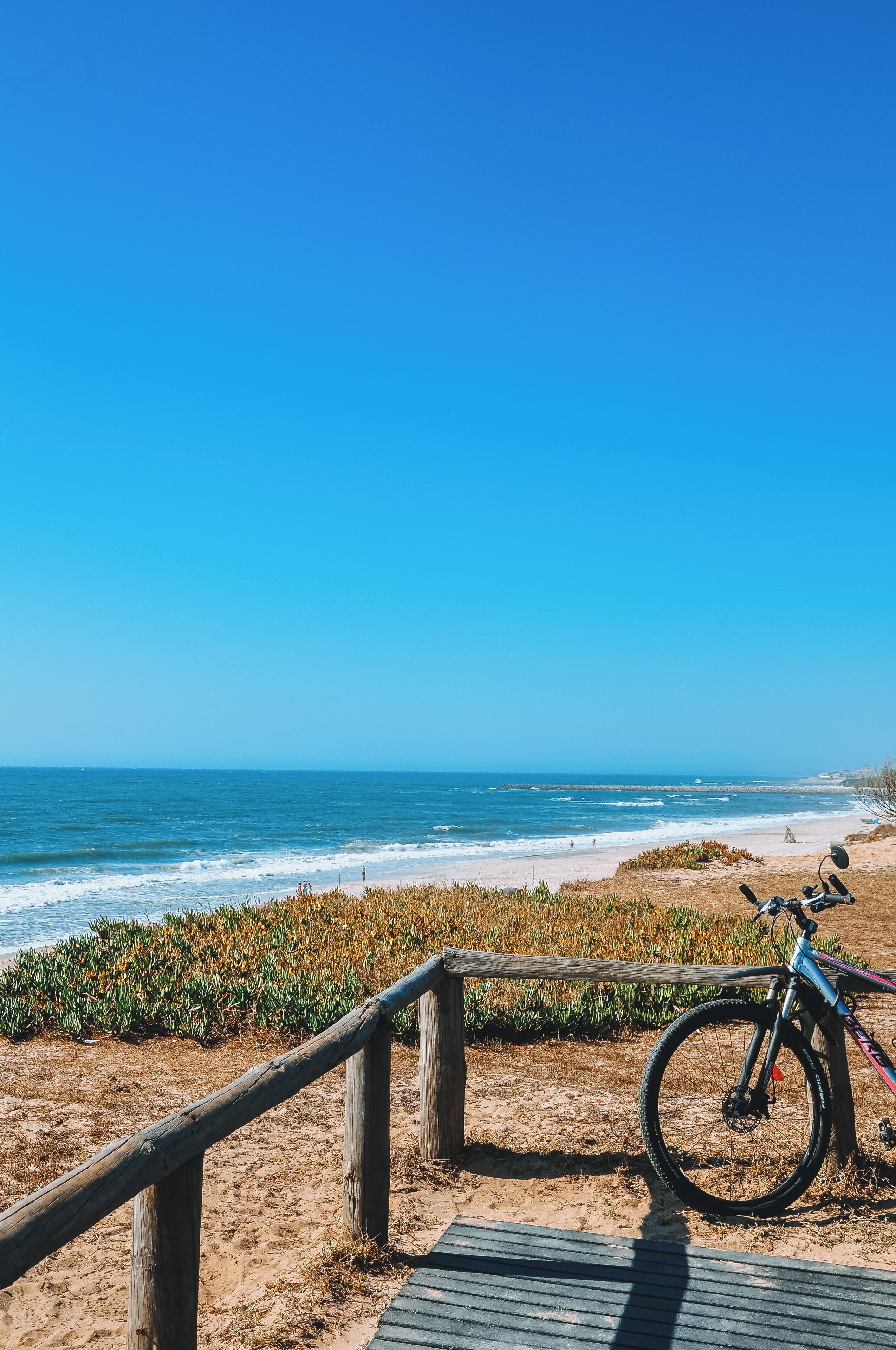 Une plage avec une promenade en bois et un vélo garé dessus.