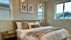Une chambre à coucher avec un grand lit, une table de chevet, une commode et deux cadres photos fixés au mur.