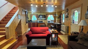 Ein gemütliches Blockhaus-Interieur mit einer Holztreppe, einem roten Sofa, einem kleinen Tisch und einer Küchenzeile.