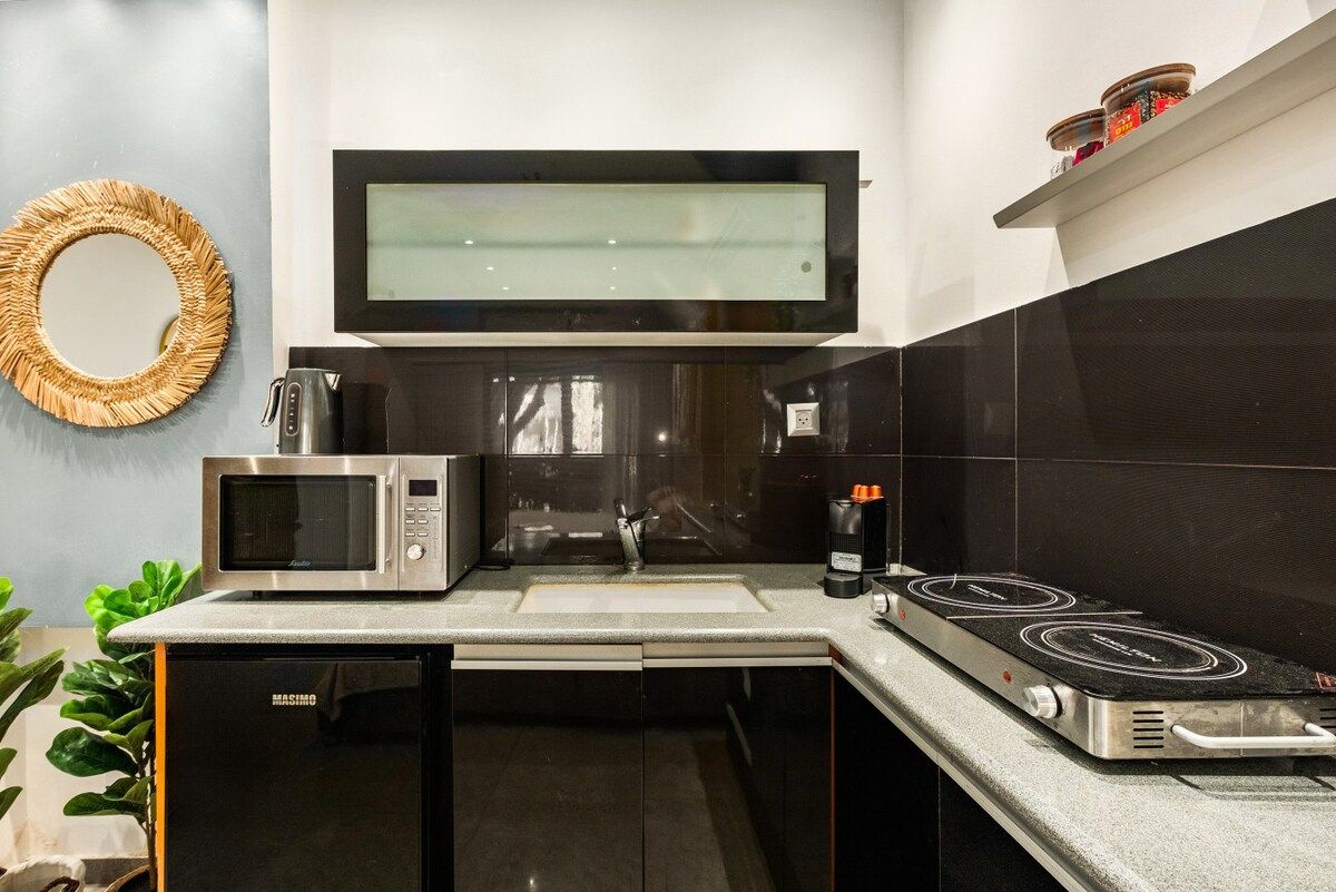 A modern kitchen with a built-in microwave, a coffee maker, and a stove.