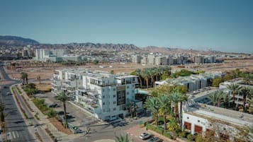 A multi-story building with a flat roof, surrounded by palm trees and a clear sky.