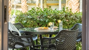 Un área de comedor al aire libre con una mesa redonda y cuatro sillas, rodeada de follaje.