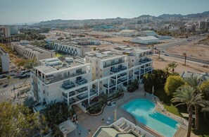 Ein modernes Hotel mit mehreren Etagen, einem Schwimmbad und Blick auf die umliegende Stadtlandschaft.