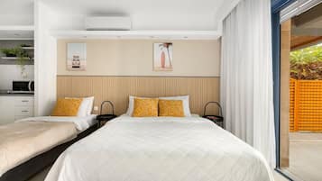Ein modernes Schlafzimmer mit zwei Betten, einem Einbauschrank, einem großen Fenster und einer Schiebetür zu einem Außenbereich.