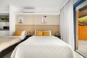 Ein modernes Schlafzimmer mit zwei Betten, einem Einbauschrank, einem großen Fenster und einer Schiebetür zu einem Außenbereich.