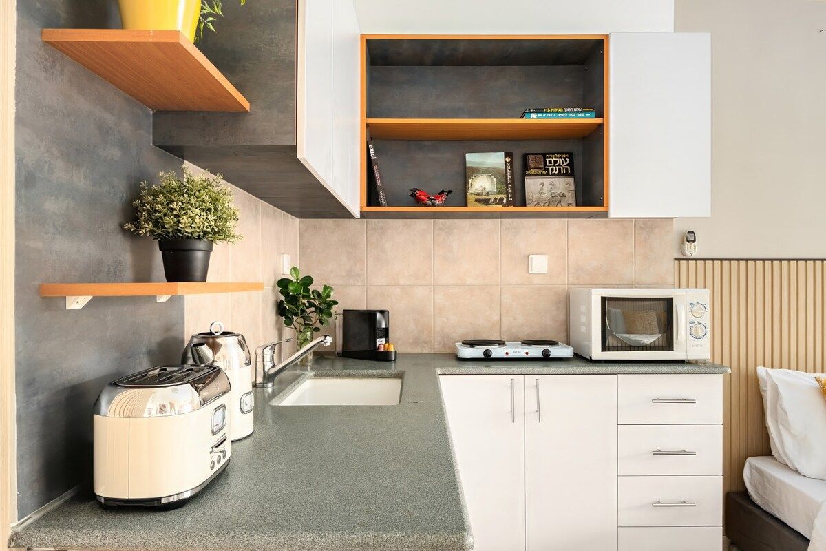Eine kompakte Küche mit Toaster, Wasserkocher, Mikrowelle und einem kleinen Schrank.