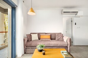 A living room with a sofa, a coffee table, a hanging light, and an air conditioning unit.
