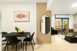 A modern living room with a dining area, a large mirror, and a view of the outdoors.