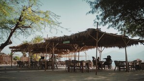 An outdoor seating area with thatched umbrellas and wooden tables. - Bright 1BR Royal Park Apt with Garden View (Eilat)
