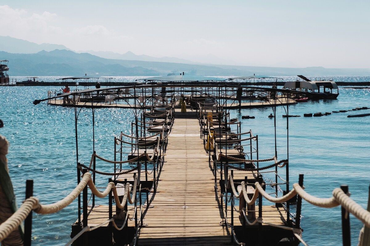 A wooden pier leading to a circular dock with seating arrangements.