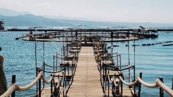 A wooden pier leading to a circular dock with seating arrangements.