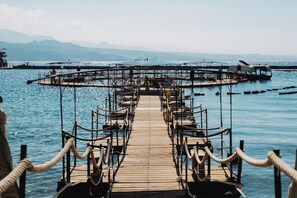 A wooden pier leading to a circular dock with seating arrangements. - 1BR Royal Park Apt • Garden View by SeaNRent (Eilat)