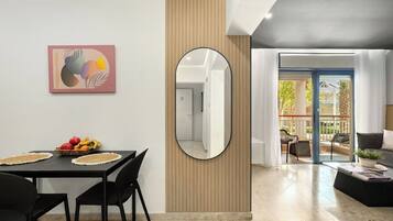 A modern living room with a dining area, a large mirror, and a view to the outside.