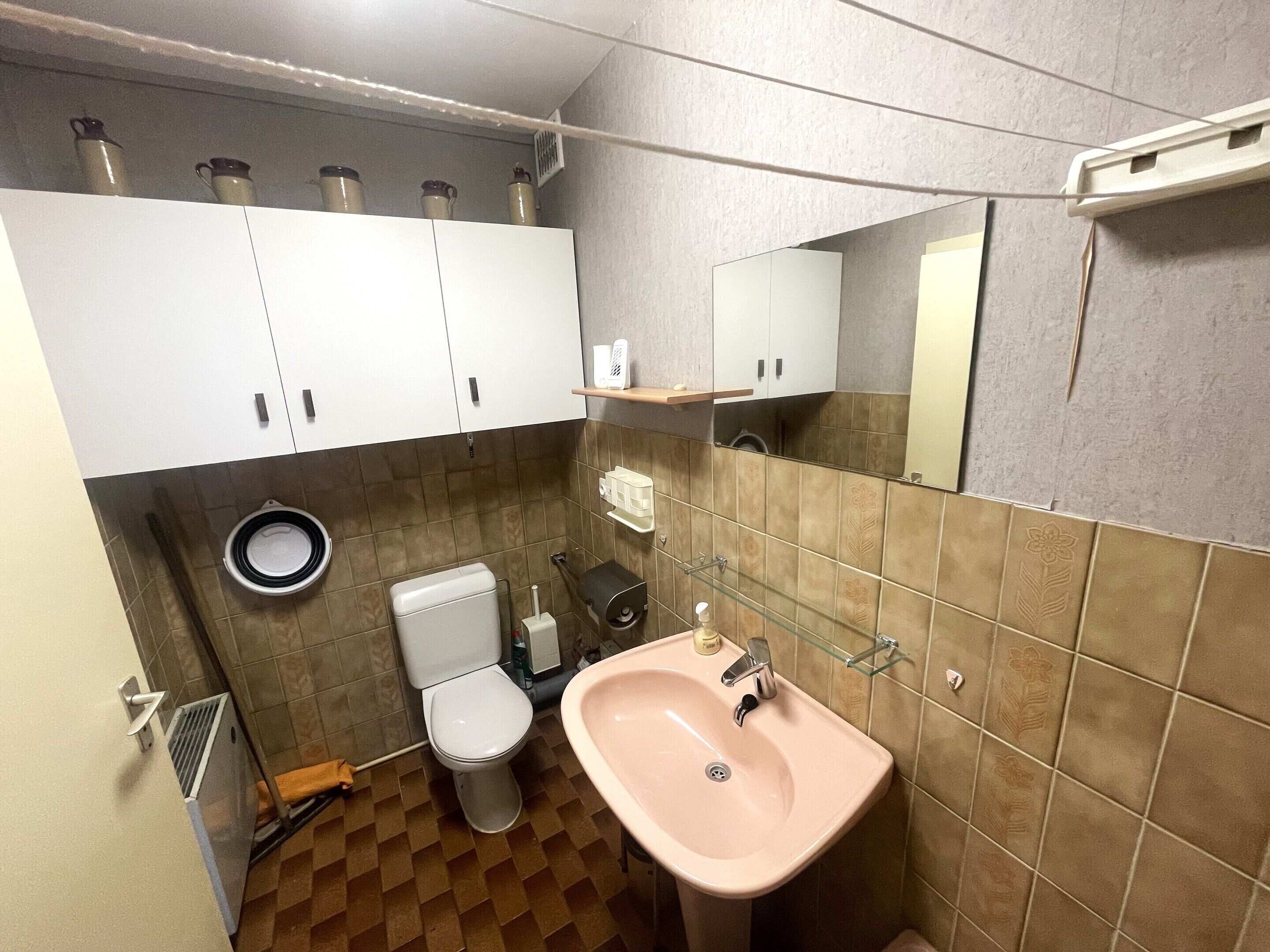 A bathroom with a toilet, sink, and cabinets.