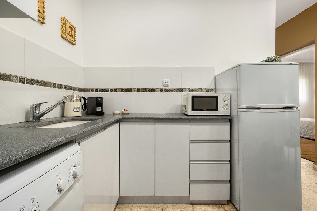 Eine kleine Küche mit einer Mikrowelle, einer Kaffeemaschine und einem Kühlschrank.