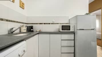Eine kleine Küche mit einer Mikrowelle, einer Kaffeemaschine und einem Kühlschrank.