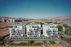 Un moderno complejo de apartamentos con varios pisos, balcones y una zona de estacionamiento.