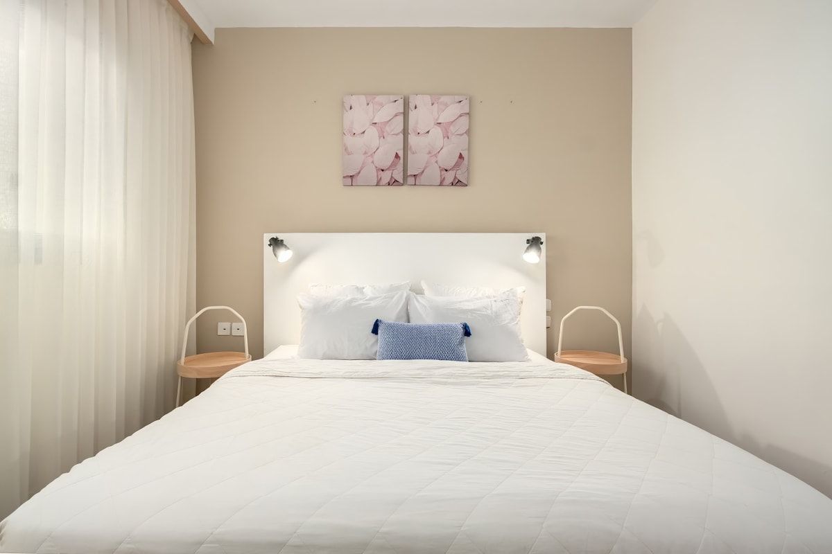 Ein Schlafzimmer mit einem Bett, Nachttischen, einer Kopfteil und Wandbildern.