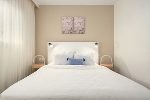 Un dormitorio con cama, mesitas de noche, cabecera y decoración en la pared.