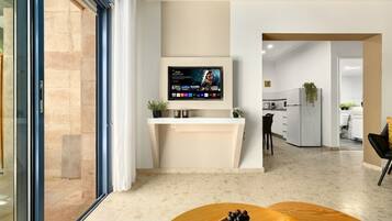 Eine moderne Küche mit integriertem Fernseher, einem Essbereich mit Obstschale und Blick auf den Wohnbereich.
