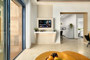 Una cocina moderna con televisor integrado, un comedor con frutero y vistas al área de estar.