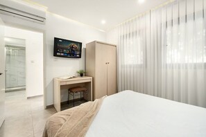 Ein modernes Schlafzimmer mit einem Bett, einem Schreibtisch, einem Fernseher und einem Kleiderschrank.