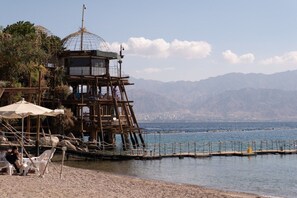 A wooden structure with a glass dome, overlooking a body of water and mountains.