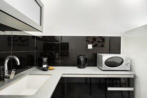 A modern kitchen with a stainless steel sink, a microwave, and a coffee maker on the countertop.