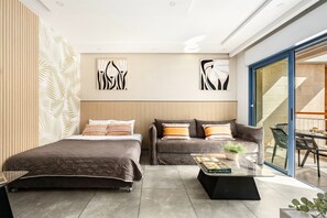 Un dormitorio moderno con cama, sofá y una mesa de centro con libros y una planta.