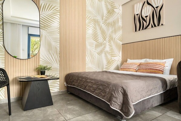A bedroom with a bed, a bedside table with a book and a plant, a mirror, and a wall with a leaf pattern.