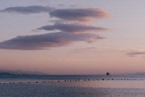 A calm sea with a boat in the distance and a line of rocks in the foreground. - Serene Royal Park Stay | Comfort & Ease (Eilat)
