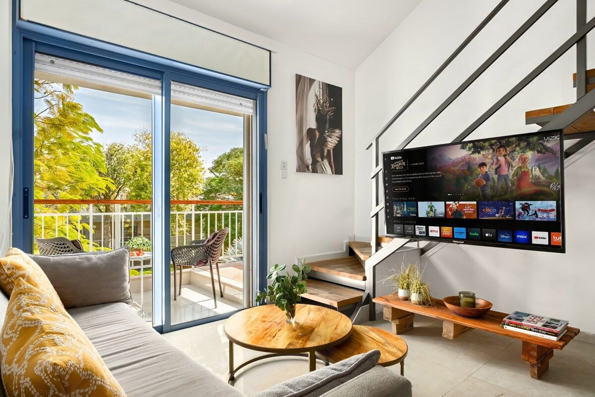 Ein modernes Wohnzimmer mit einer Couch, einem Couchtisch und einem an der Wand befestigten Flachbildfernseher.