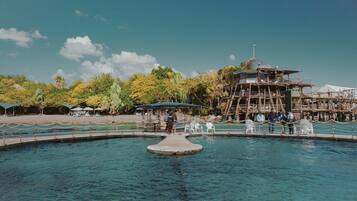 Ein Pool mit einer zentralen Insel, umgeben von einer Holzdielen-Terrasse und einem Wachturm-Gebäude.