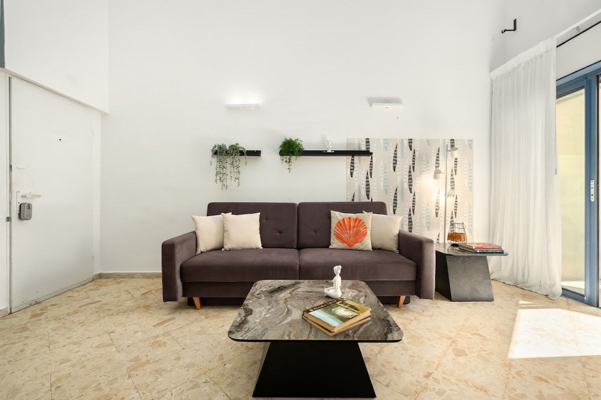 Ein modernes Wohnzimmer mit einer Couch, einem Couchtisch und einem Bücherregal.