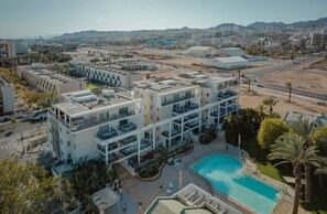 Un hotel moderno con varios pisos, una piscina en la azotea y vistas de la ciudad.